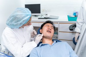 Caucasian dentist examine tooth for young man patient at dental clinic.