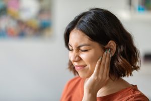 Woman Experiencing Ear Pain Touching Her Face