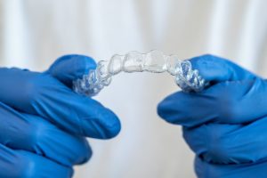 Close-up of blue gloved hands holding a clear aligner tray