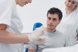 Dental professional showing a clear aligner tray to a male patient seated in a dental chair while an assistant looks on
