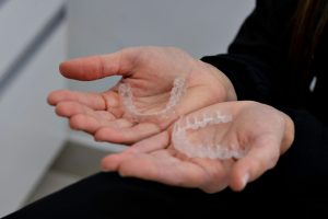 Open palms holding an upper and a lower clear aligner tray